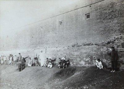 People in Jallianwala Bagh pointing at bullet marks on the wall surrounding the Bagh