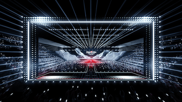 Photograph of a stage that is brightly lit with the words Eurovision Song Contest on the screen.  