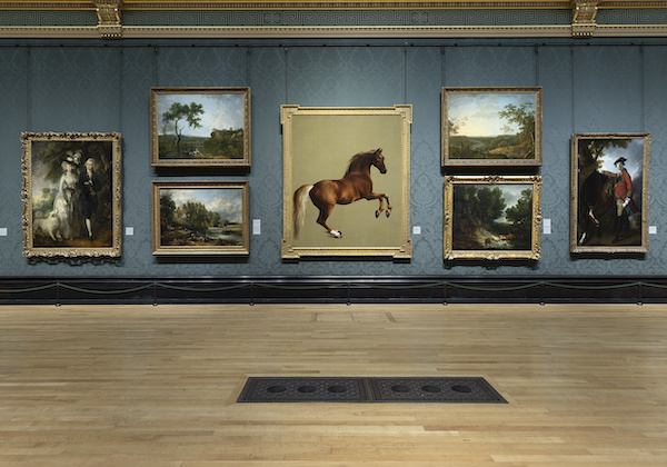 Photograph of one of the National Gallery rooms, it has blue walls and light wooden floor on the wall are 7 large paintings showing portraits and landscapes. In the centre is a painting of a horse, it is chestnut coloured and rearing up on its hind legs.  