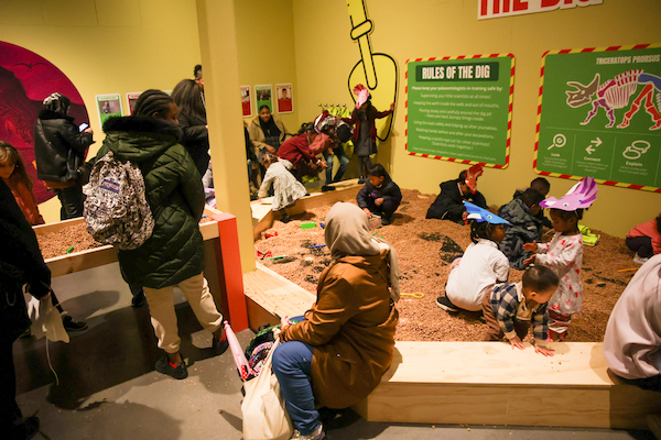 Photograph of families playing in a giant sand pit in an exhibition. 